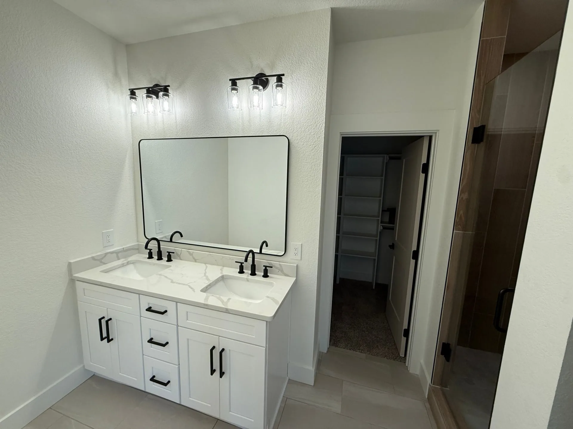 Bathroom with a white double vanity, black fixtures and a black-framed mirror