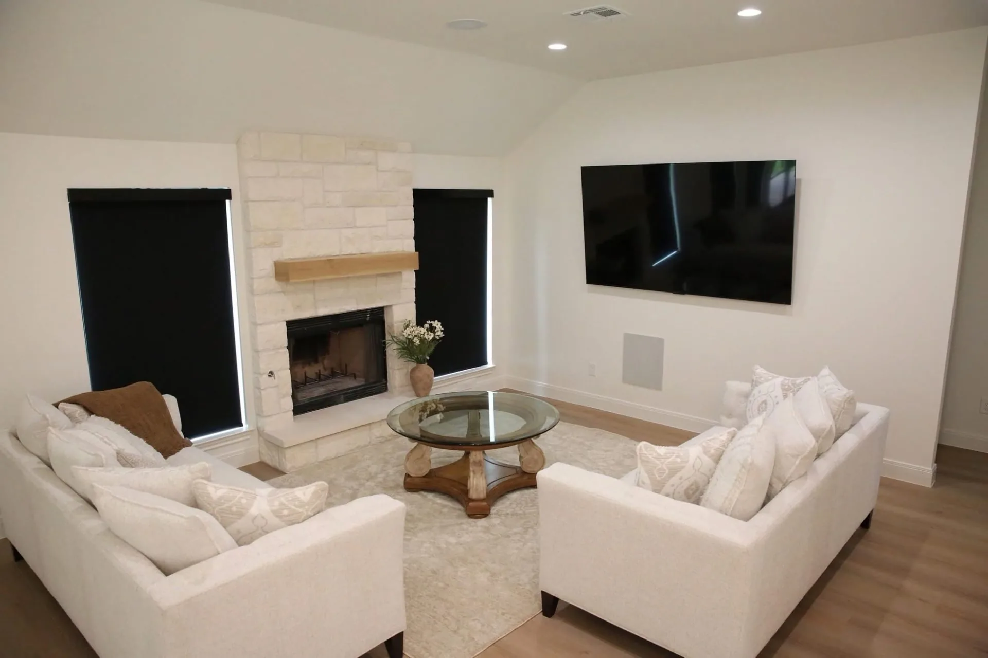 Living room with a white stone-look fireplace, a wood-tone mantel and white sofas